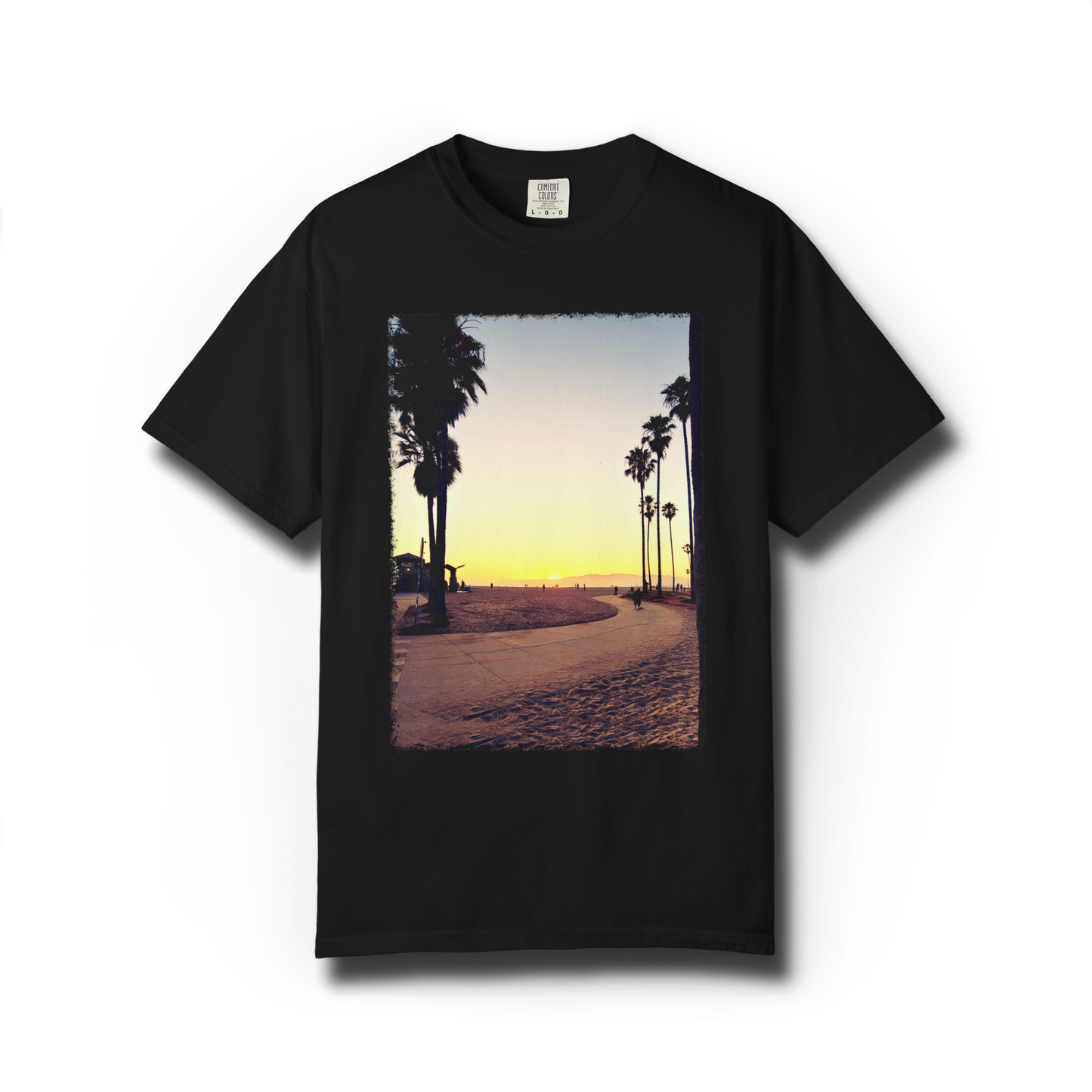 Black graphic t-shirt of Venice Beach with a beach, palm tree, and sunset design on a white background