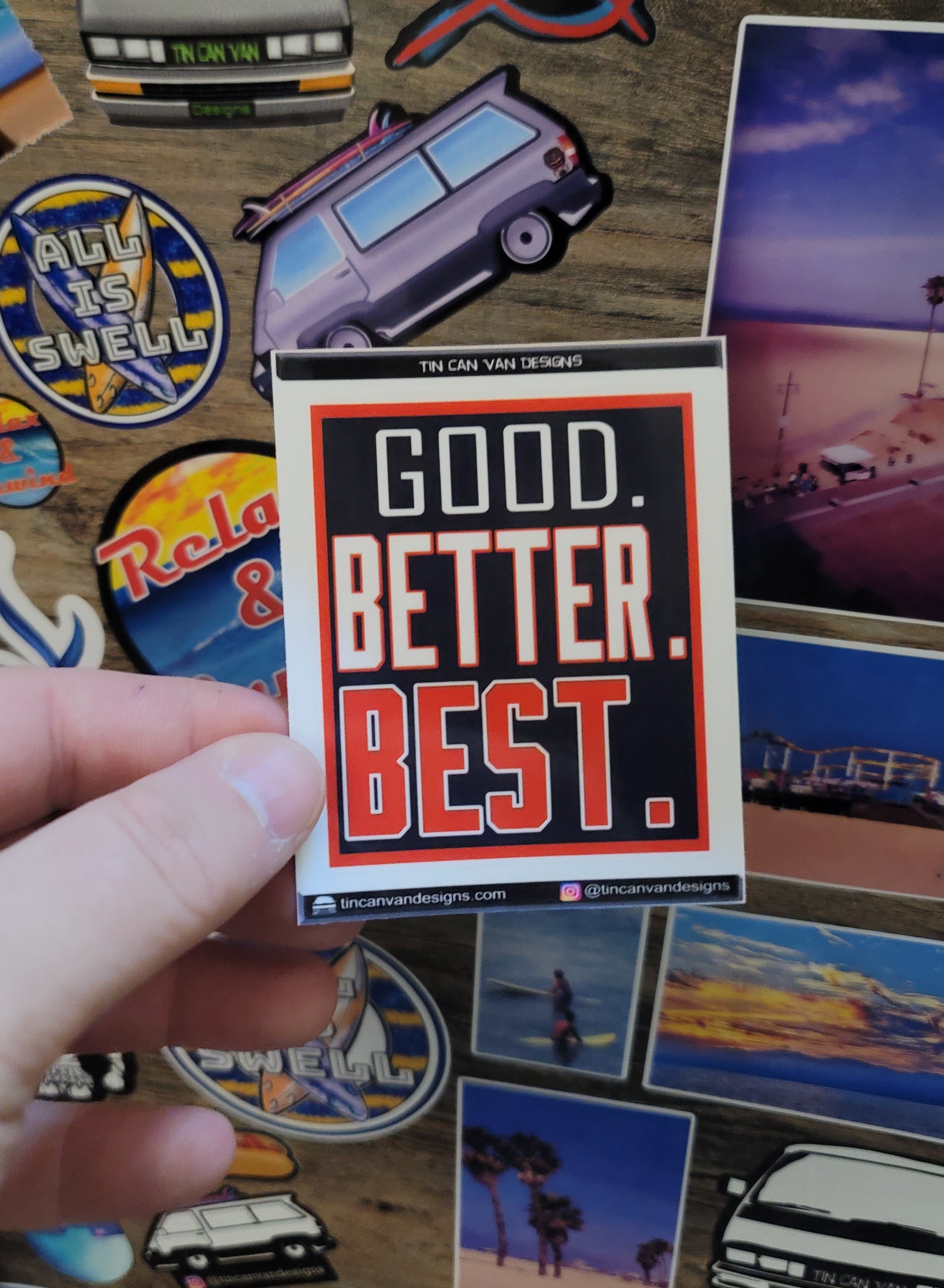 2.75" x 3" Sticker with 'Good. Better. Best.' text held over a collection of other stickers.