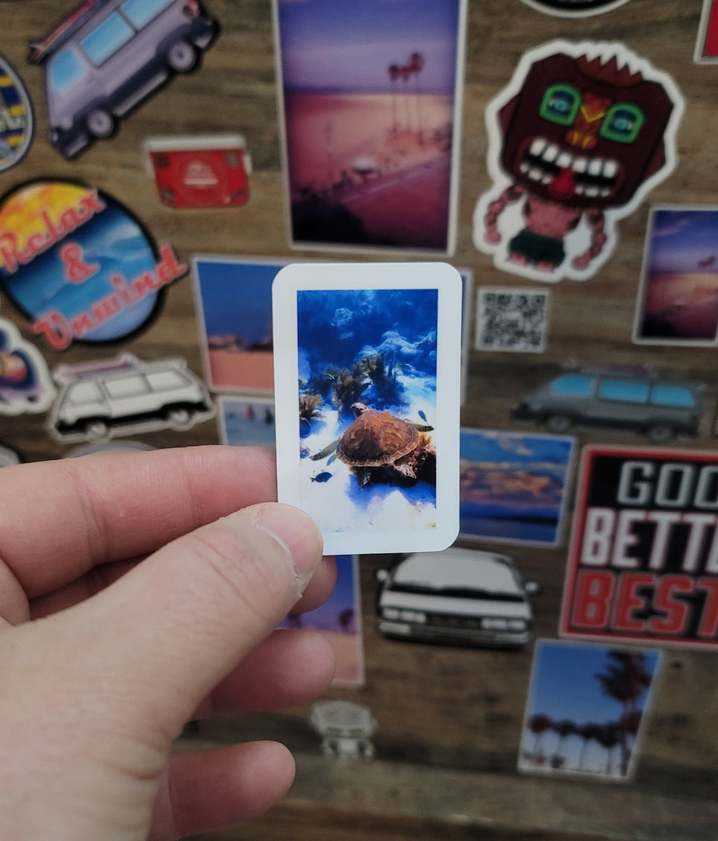 Hand holding a vinyl photo  sticker of a sea turtle taken while scuba diving in Key Largo Florida.