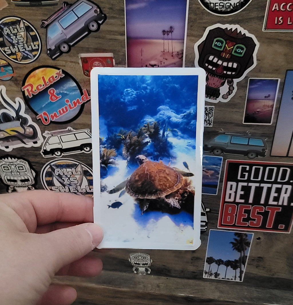 Hand holding a vinyl photo  sticker of a sea turtle taken while scuba diving in Key Largo Florida.