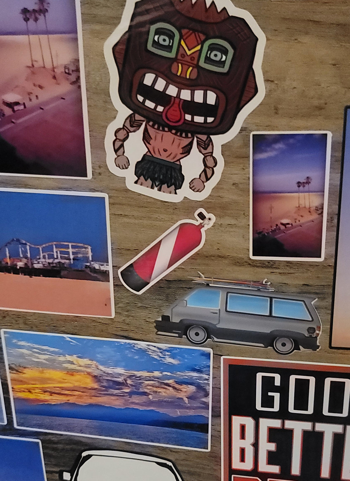 Collection of stickers on a wooden surface with beach-themed images with a red and white dive flag scuba tank in the middle.