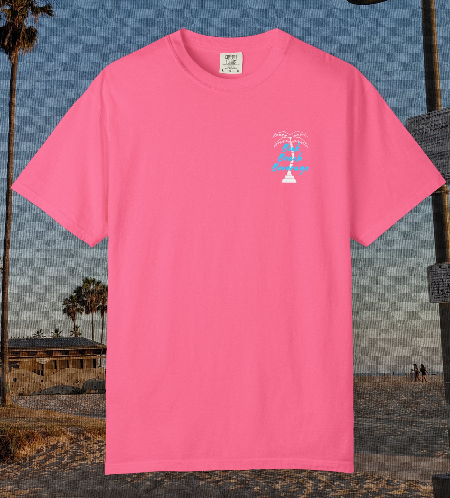 Comfort Colors cotton t-shirt Crunch Berry Pink in color featuring durable DTF front left chest design design of a white palm tree and the words Book Beach Beverage in orange.