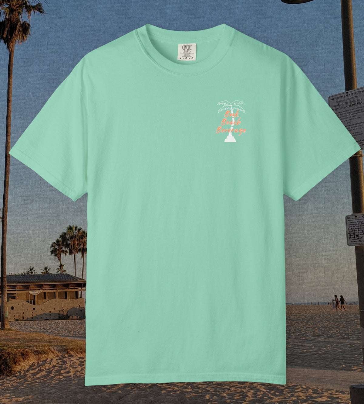 Comfort Colors cotton t-shirt Island reef green in color featuring durable DTF front left chest design design of a white palm tree and the words Book Beach Beverage in orange.
