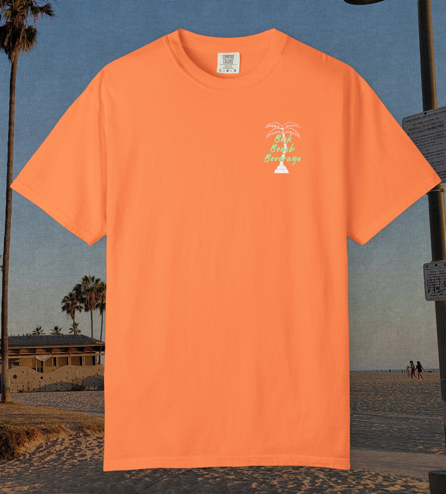 Comfort Colors cotton t-shirt Melon orange in color featuring durable DTF front left chest design design of a white palm tree and the words Book Beach Beverage in light green.