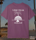 A berry color t-shirt shown from the back, featuring a white graphic of a palm tree and a striped semi-circle with the text 'LONE PALM SOCIAL CLUB'. The shirt is displayed against a beach background with a 'BACK DESIGN' label in the bottom right corner.