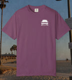 A berry short-sleeve t-shirt with a small white graphic of a car on the left chest, displayed against a beach background.