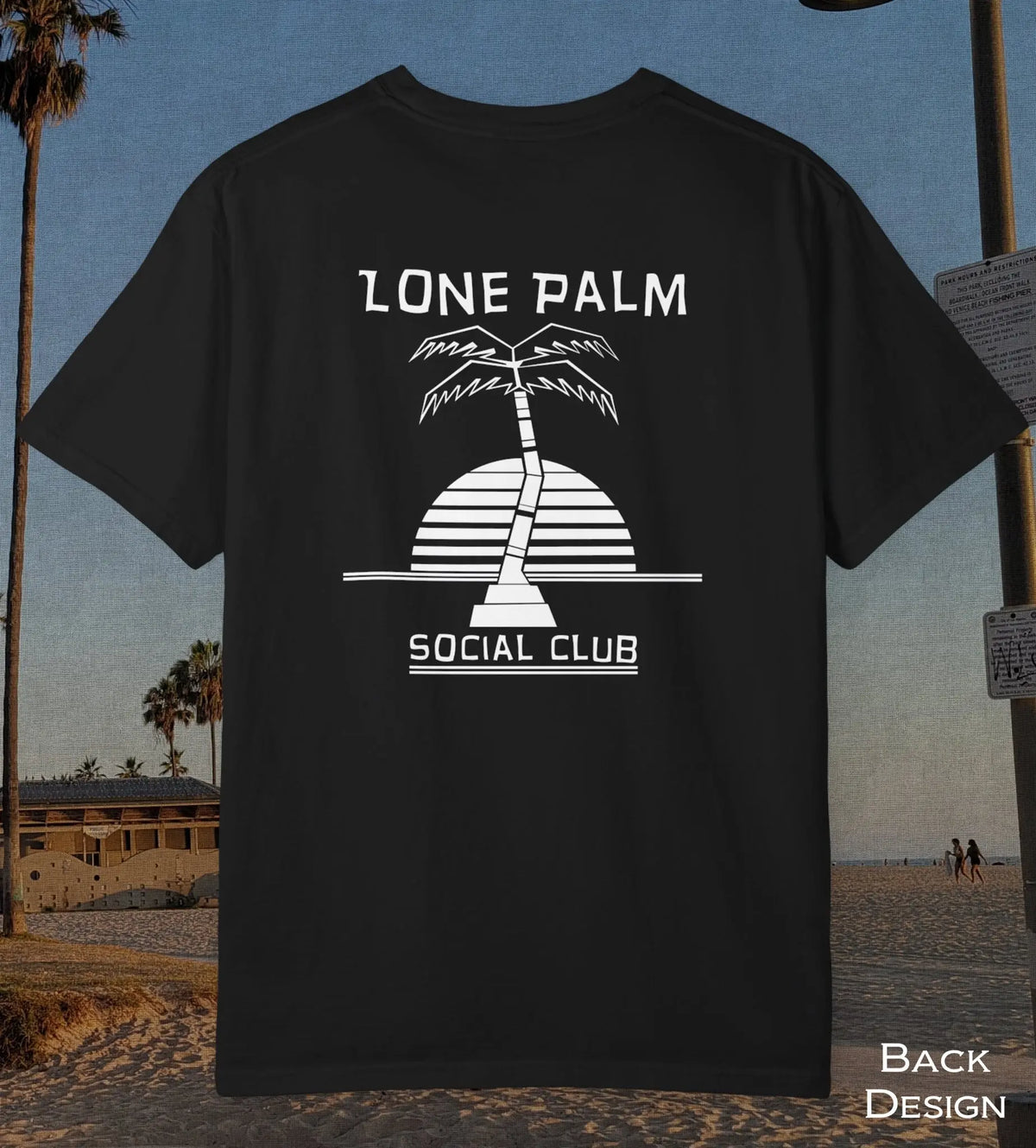 A black short-sleeve t-shirt with a white graphic print of a palm tree and the text 'LONE PALM SOCIAL CLUB' on the back, displayed against a beach background.
