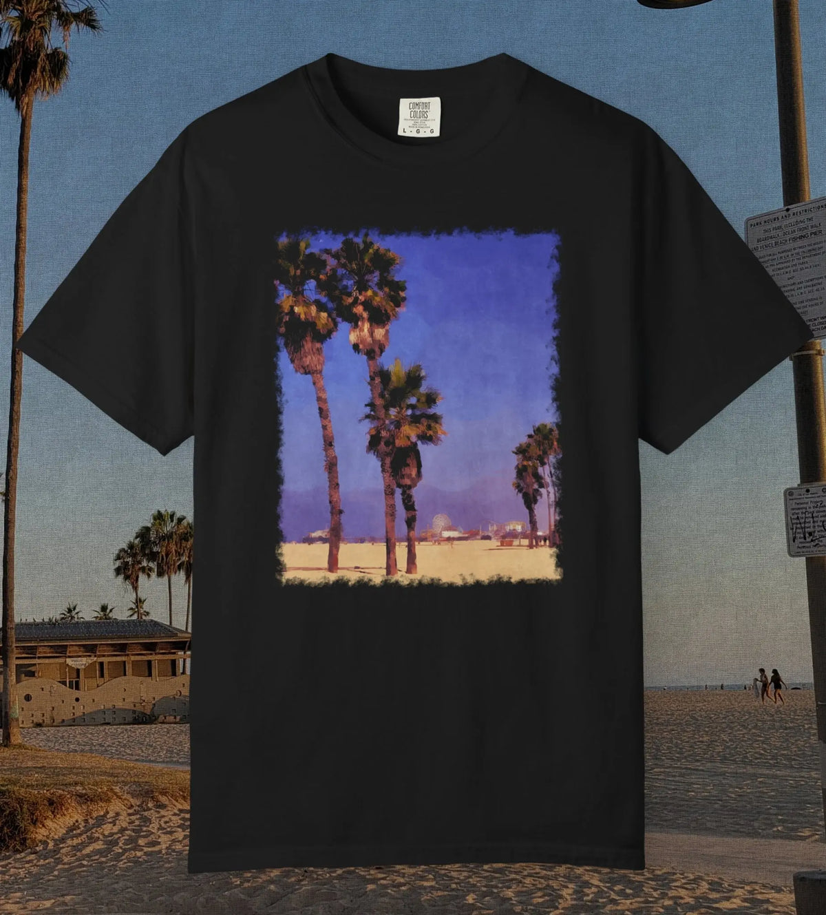 Comfort Colors 100% cotton black t-shirt featuring a durable DTF transfer of the Santa Monica Pier in the distance framed between multiple palm trees on the beach.