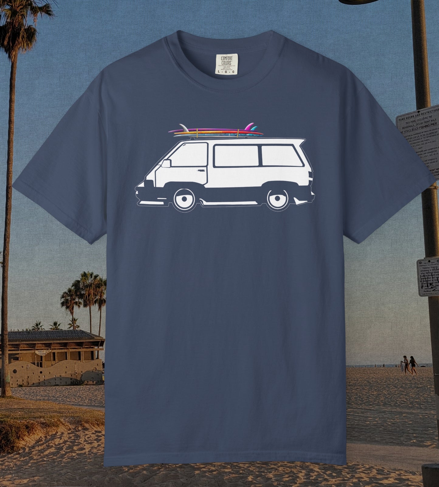 A navy blue short-sleeve t-shirt featuring a graphic of a white van with pink and red surfboards on its roof, set against a beach background.