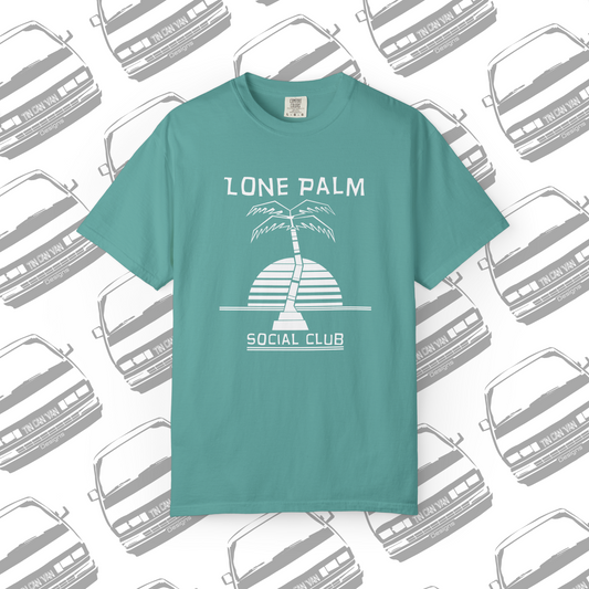 Sea foam green teal Comfort Colors graphic t-shirt with DTF  'Lone Palm Social Club' palm tree graphic on a background with van silhouettes.