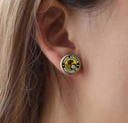 A close-up of a person's ear wearing a round stainless steel earring featuring the Carol Stream Panthers Soccer Club Logo.