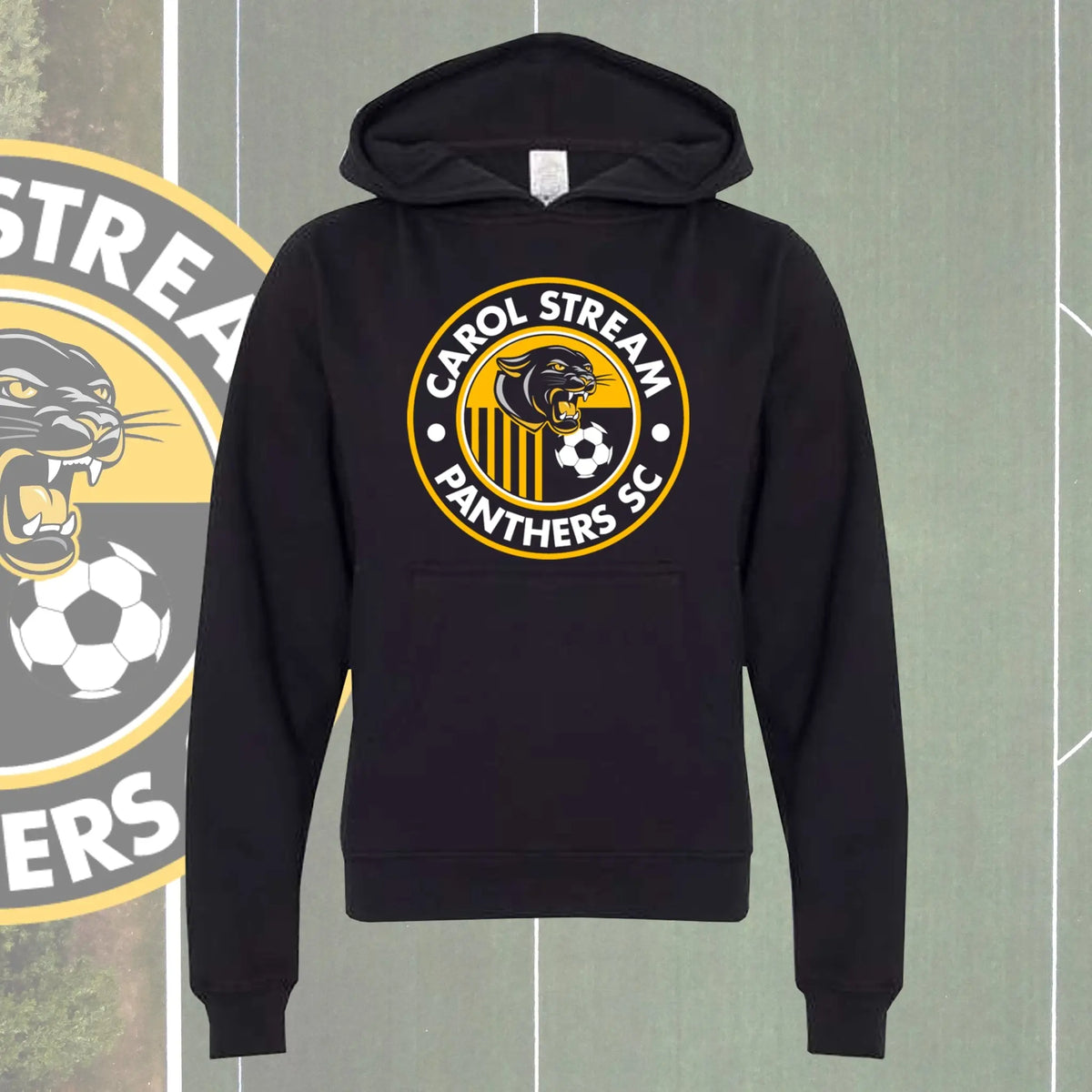 A youth black pullover hoodie featuring a circular 'Carol Stream Panthers SC' graphic on the chest, displayed against a green soccer field background with a team logo partially visible on the left.